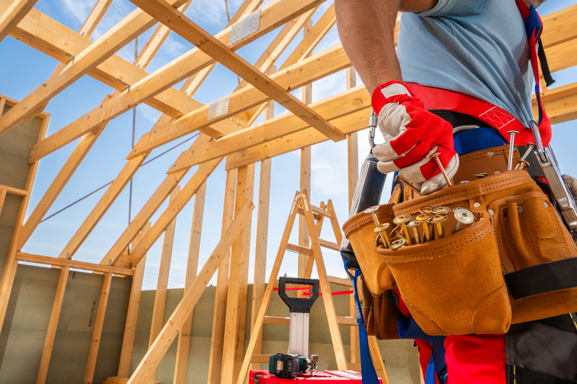 Construction Worker Preparing Tools Inside a Wooden Frame Structure on a Clear Day